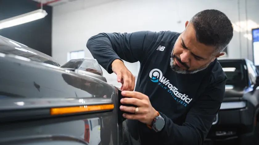 WrapTastic technician fitting paint protection film around a vehicle’s front panel