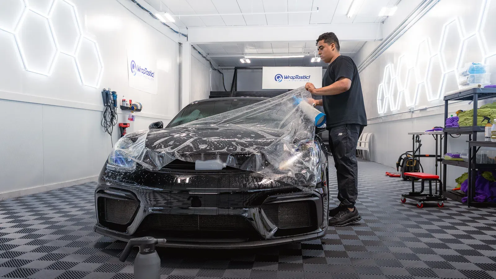Technician applying paint protection film to a Porsche inside a WrapTastic shop